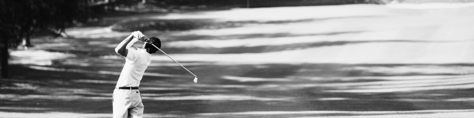 image of a golfer taking a swing at the tee box. black and white image.